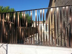 the gate is made of metal and has vertical bars on it, along with a stone building in the background