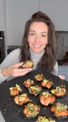 a woman is holding up some food on a tray in her hands and smiling at the camera