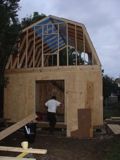 a man standing in the doorway of a house under construction with wood framing around it