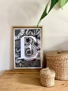 a wooden table topped with a plant next to a framed letter b on top of a wall