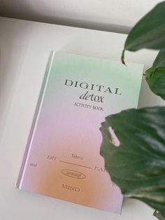 a book sitting on top of a white table next to a green leafy plant