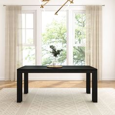 a black table sitting in front of a window next to a white rug on top of a hard wood floor