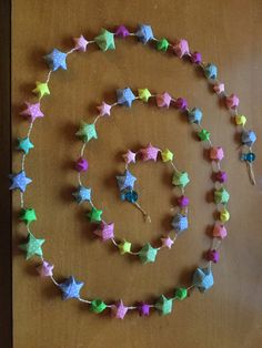 a wooden table topped with colorful stars on it's side and a string of beads hanging from the end