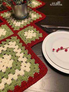 a crocheted placemat with red and green balls on it next to a white plate