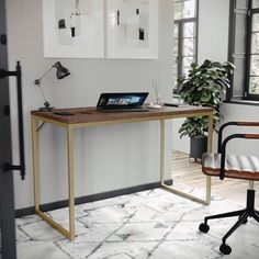 a laptop computer sitting on top of a wooden desk next to a chair and potted plant