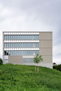 an office building sitting on top of a lush green hillside