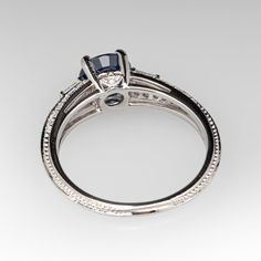 This finely detailed ring is centered with a four-prong set round brilliant cut natural blue sapphire. The split shoulders are each topped with one (1) channel set tapered baguette cut diamond. The shank is accented with four-rows of seven (7) bead set round brilliant cut diamonds. The profile of the ring is accented with one (1) bead set round brilliant cut diamond on each side. The ring measures 6.9mm at the top, rises 5.9mm above the finger, tapering to 2.1mm wide and 1.6mm thick at the base Luxury Lab-created Sapphire Ring With Diamond Cut, Timeless Sapphire Ring With Diamond Baguette Cut, Luxury Sapphire Ring With Brilliant And Baguette Cuts, Timeless Sapphire Baguette Cut Ring With Diamond Details, Timeless Sapphire Baguette Cut Ring, Asscher Cut Sapphire Ring With Diamond Detail, Elegant Lab-created Sapphire Ring With Brilliant Cut, Elegant Brilliant-cut Lab-created Sapphire Ring, Elegant Brilliant Cut Lab-created Sapphire Ring