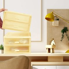 a person holding a box over a desk with a chair and other items on it