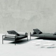 two black and white couches sitting next to each other in front of a concrete wall