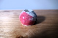 a white and red vase sitting on top of a wooden table