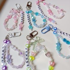 several different bracelets with charms and name tags attached to them on a white surface