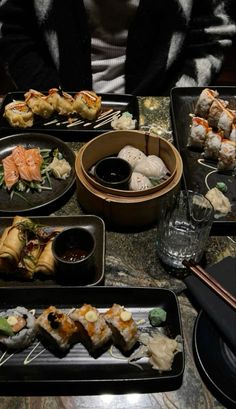 a table topped with black trays filled with sushi