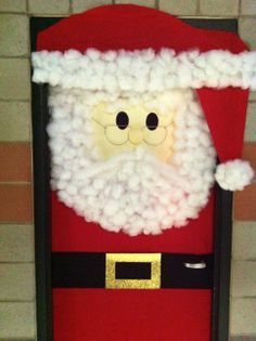 a santa claus door decoration on the side of a building with a brick wall behind it