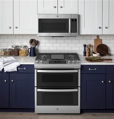 two ovens in a kitchen with blue cabinets and white counter tops, one is built into the wall