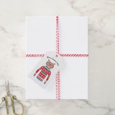 a gift wrapped in white paper with a red and white striped ribbon