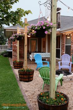 some chairs are sitting on the gravel in front of a house with flowers and lights