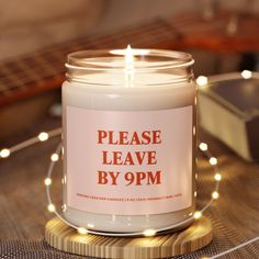 a white candle sitting on top of a wooden table next to a string of lights