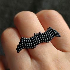 a person's hand with a beaded ring on their finger that is shaped like a dog