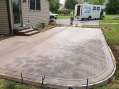 a man standing in front of a house next to a driveway with a large concrete slab