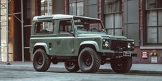 a green land rover is parked in front of a building