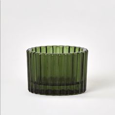 a green glass vase sitting on top of a white table next to a black object