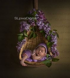 a baby sleeping in a basket with purple flowers