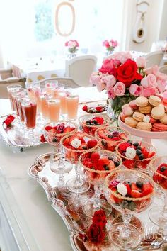 a table topped with lots of desserts and cups filled with flowers on top of it