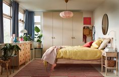 a bed room with a neatly made bed next to a dresser and mirror on the wall