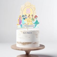 there is a white cake that has the number five on it and princesses on top