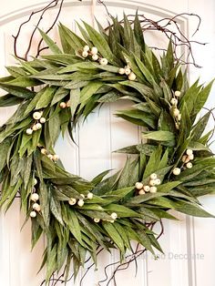 a wreath with white berries and green leaves hangs on the front door's wall