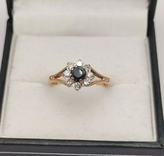 an engagement ring in a box with its lid open showing the diamond and sapphire stones