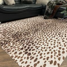 a living room with a black couch and a leopard print rug on the floor in front of it