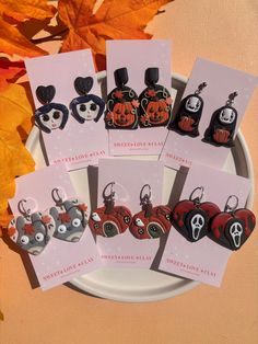 six halloween themed keychains on a plate with autumn leaves in the back ground