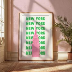 a pink and green poster with the words new york on it next to a potted plant