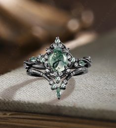 an engagement ring with a green stone surrounded by white diamonds on top of a book