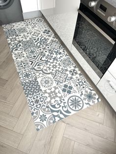 a kitchen area rug with an ornate design on the floor and oven in the background