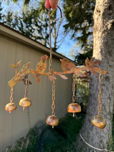 a person is holding up a wind chime that has birds hanging from it's branches