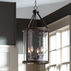 a light fixture hanging from the ceiling in a room with white walls and windows behind it