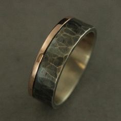 a wedding band with an unusual design in gold and black, on a gray surface