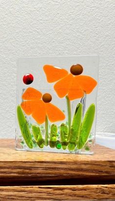 a glass vase with flowers in it sitting on a wooden table next to a white wall