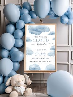 a baby shower sign next to balloons and a teddy bear in front of the frame