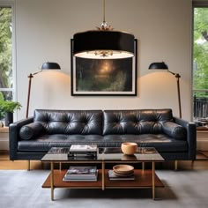 a living room with black leather couches and two lamps