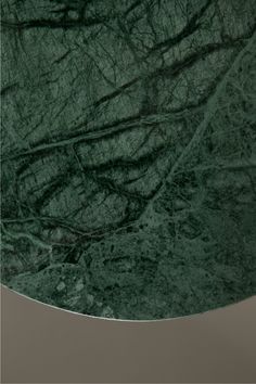 a green marble table top with black veining on the edges and an oval base