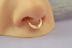 a gold nose ring with a heart on it