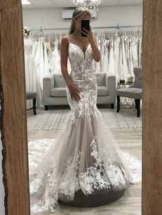 a woman taking a selfie in front of a mirror wearing a white wedding dress