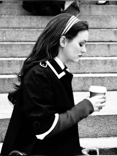 a woman is walking down the stairs with her coffee