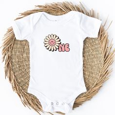 Introducing the Groovy One Daisy Baby Bodysuit - the perfect outfit to celebrate your little one's 1st birthday in style! This adorable bodysuit is designed with utmost love and care to make your baby look absolutely groovy  on their special day. Crafted from soft and breathable cotton fabric, the Groovy One Daisy Bodysuit ensures your baby's comfort throughout the day. It features a delightful daisy pattern that exudes a playful and cheerful vibe, creating a truly groovy look.  With its convenient snap-button closure at the bottom, dressing and diaper changes become a breeze. The bodysuit offers a perfect fit and allows your baby to move freely and explore their surroundings comfortably. Whether they're crawling, playing, or enjoying their first taste of birthday cake, this outfit ensures Cute Short Sleeve Onesie For First Birthday, Personalized Fitted Onesie For Birthday, Playful White Short Sleeve Bodysuit For Spring, Fitted Short Sleeve Onesie For Birthday, Pink Onesie For Birthday In Summer, Pink Onesie For Summer Birthday, Cute Unisex Bodysuit For Birthday, Personalized Cute Onesie For First Birthday, Pink Letter Print Onesie For Summer