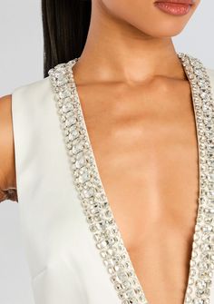 a close up of a woman wearing a white dress with pearls on the neck and shoulder