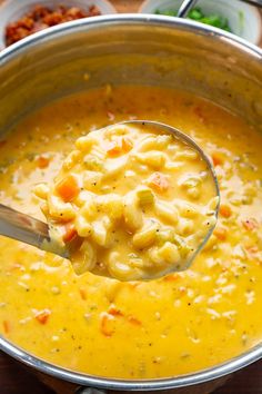 a ladle full of macaroni and cheese soup on a table with other dishes