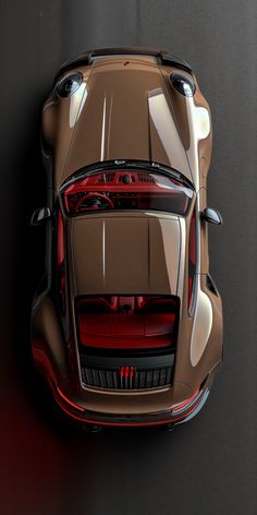 an overhead view of the rear end of a brown sports car on a black background